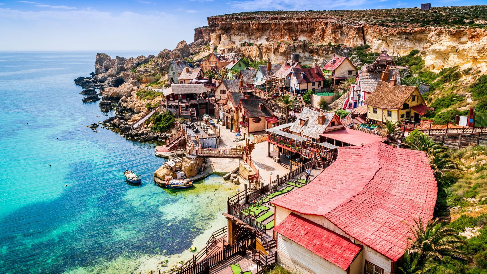 Popeye Village, Malta, colorful wooden buildings, red rooftops, and turquoise sea.