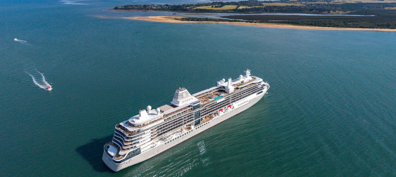 Silversea cruise ship sailing on calm blue water near a coastline, seen from above
