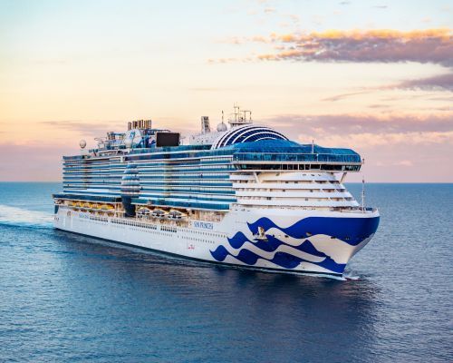 Sun Princess Cruise ship with blue wave design sailing on calm ocean at sunset