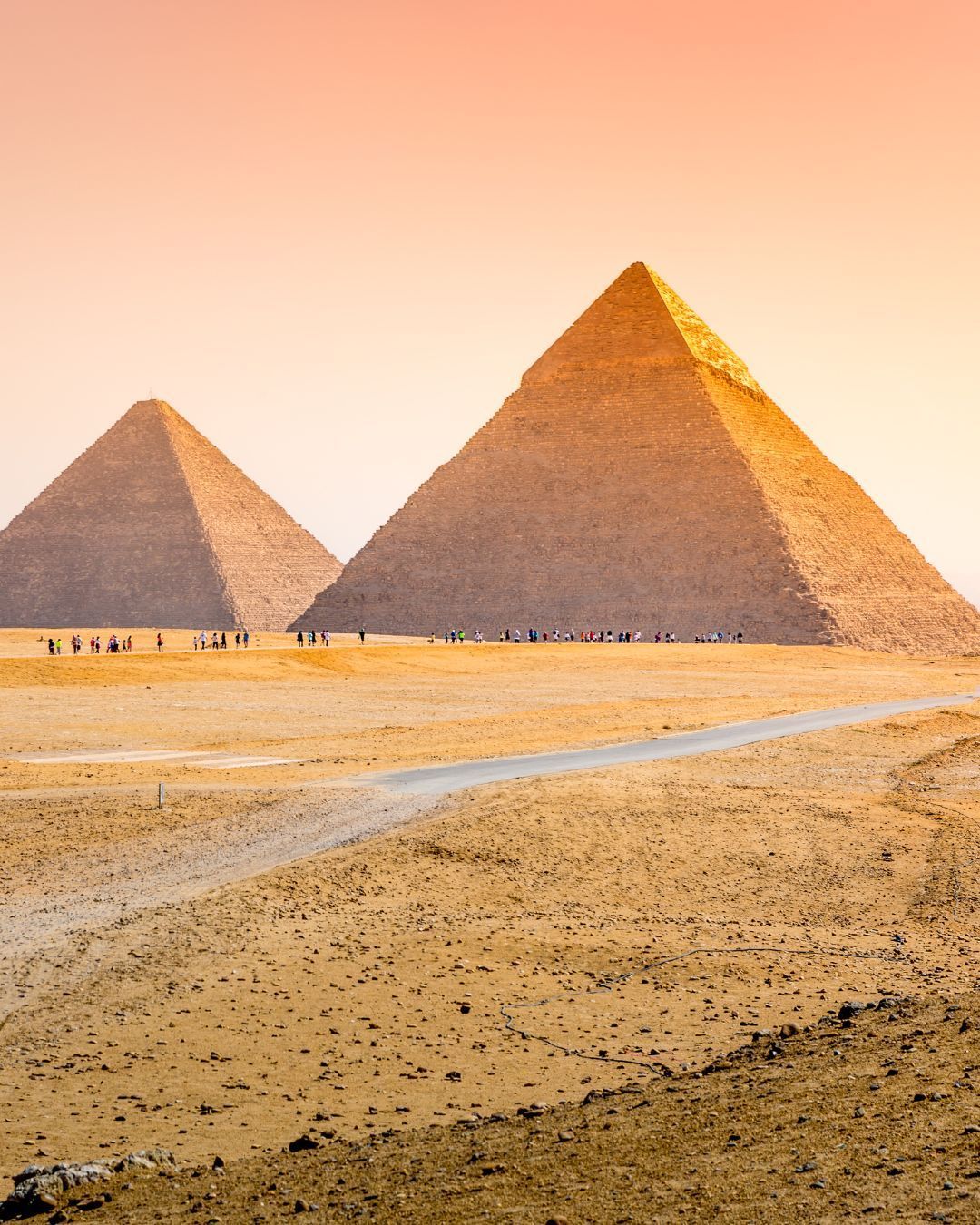 Great Pyramids of Giza at sunset with warm golden desert sands and a pink-orange sky