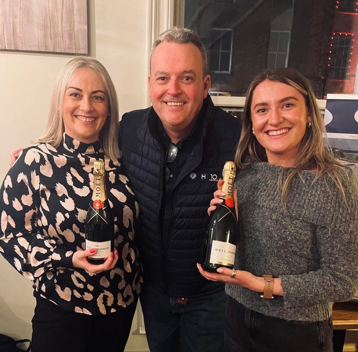 A man and two women holding bottles of moet champagne
