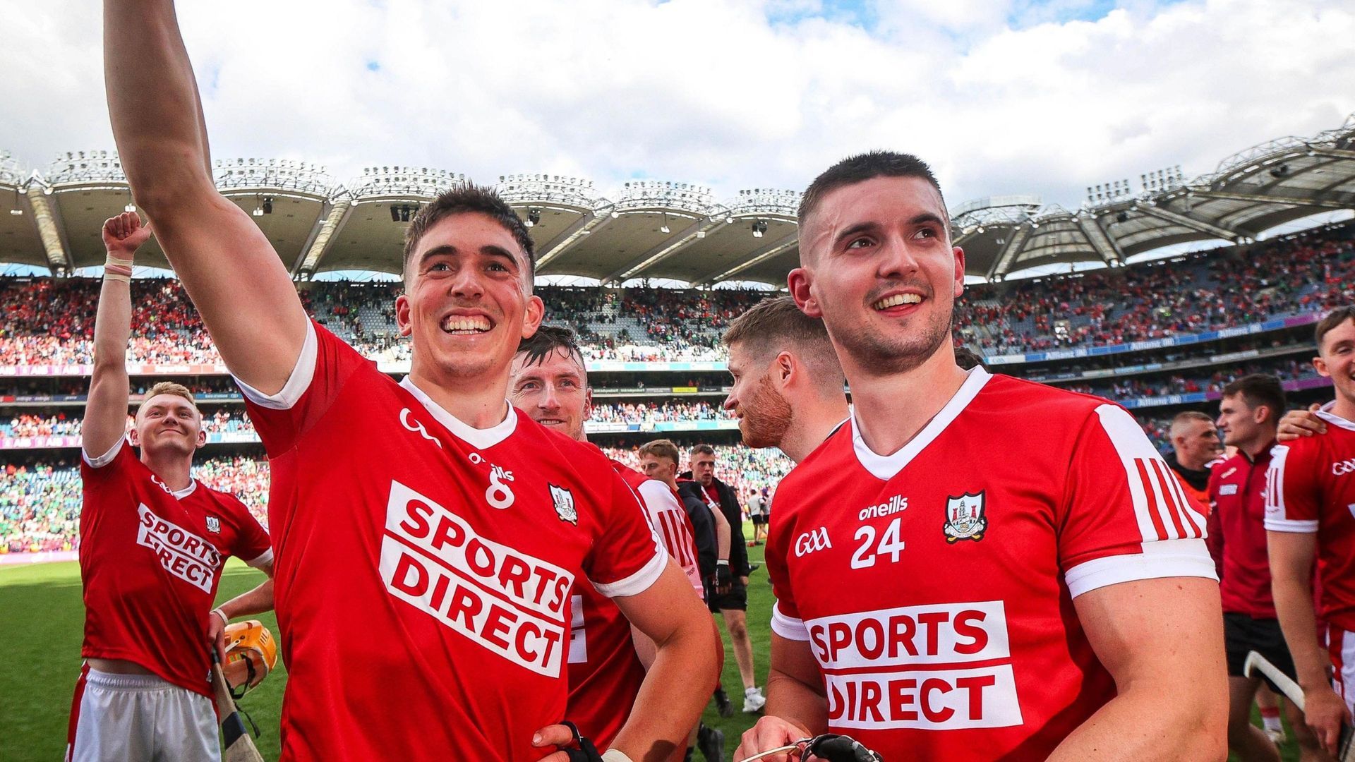 Two GAA Cork Hurling players in red jerseys celebrating on the field in a stadium