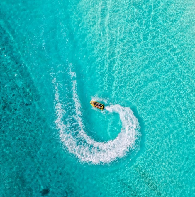 Aerial View of 2 people riding a jet ski on a beautiful turquoise blue ocean in Marbella, Malaga, Spain