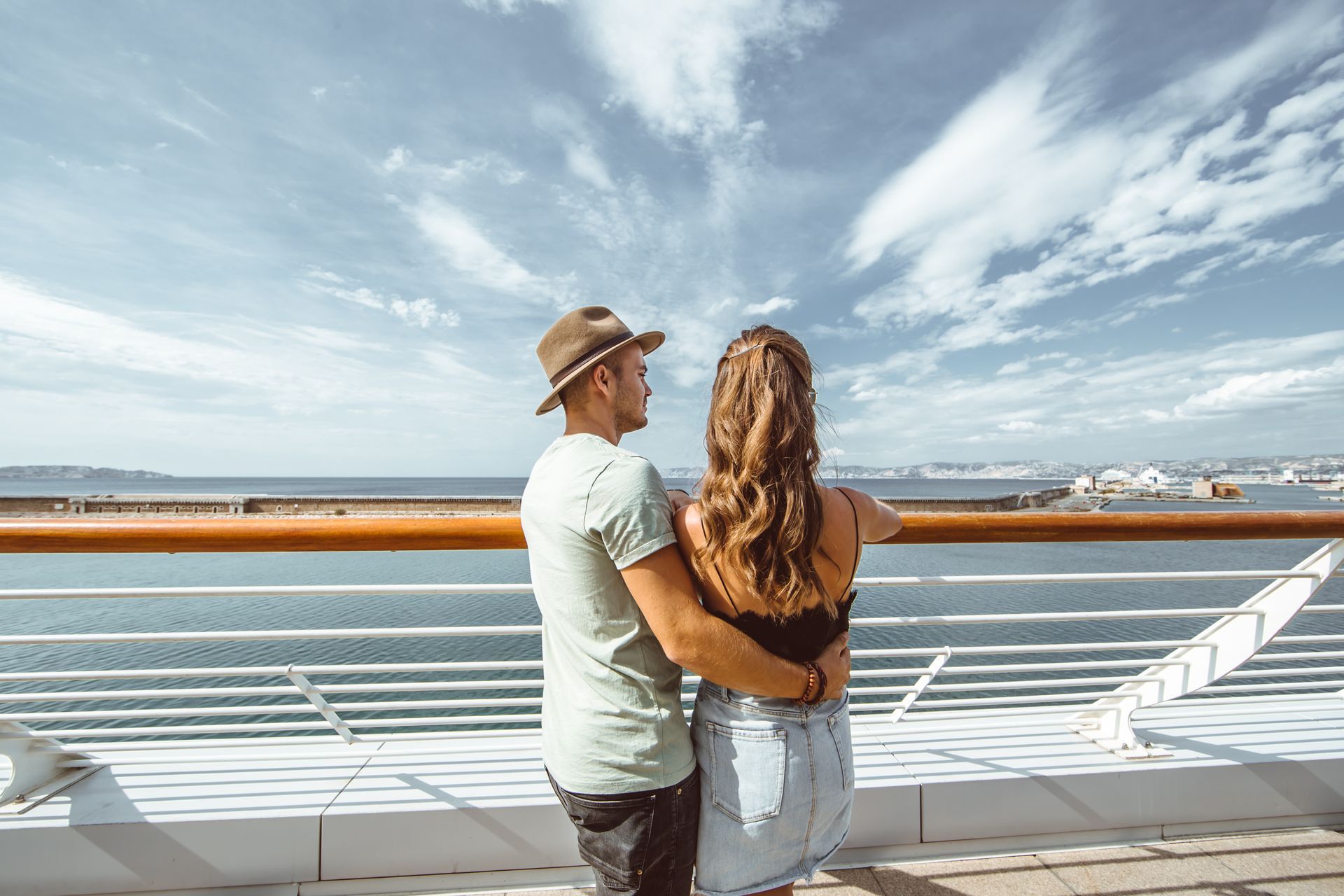 a man and a woman are standing on a cruise ship looking out over the ocean .Barter'sTravelnet