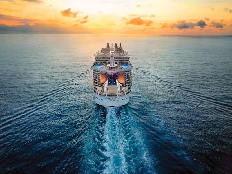 an aerial view of a cruise ship sailing in the ocean at sunset . Barter'sTravelnet