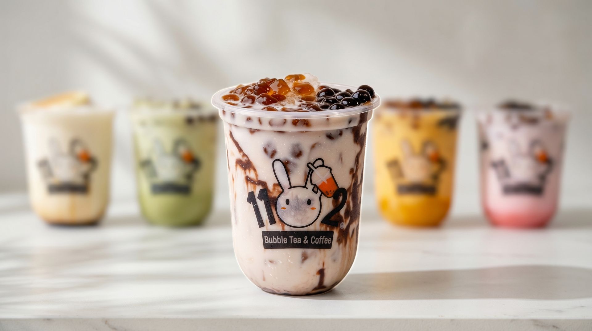 Row of colorful bubble tea cups, with a chocolate-topped drink centered in front.