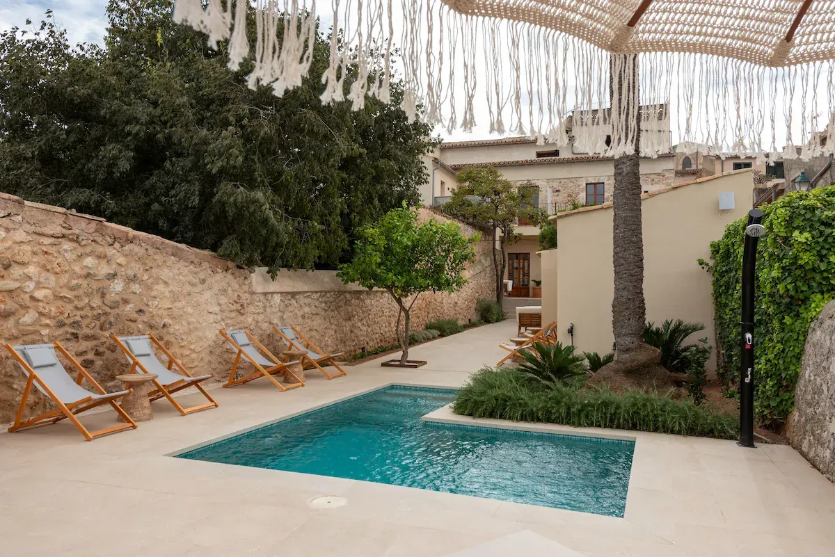 Una gran piscina está rodeada de sillas y árboles.