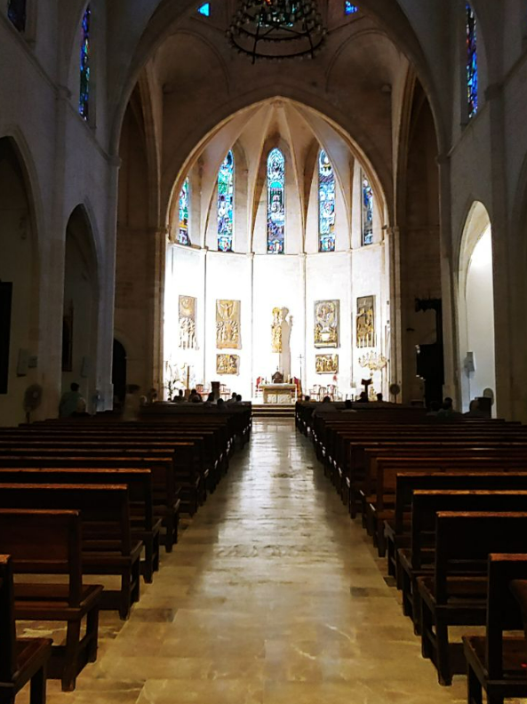 Una iglesia con filas de bancos de madera y vidrieras.