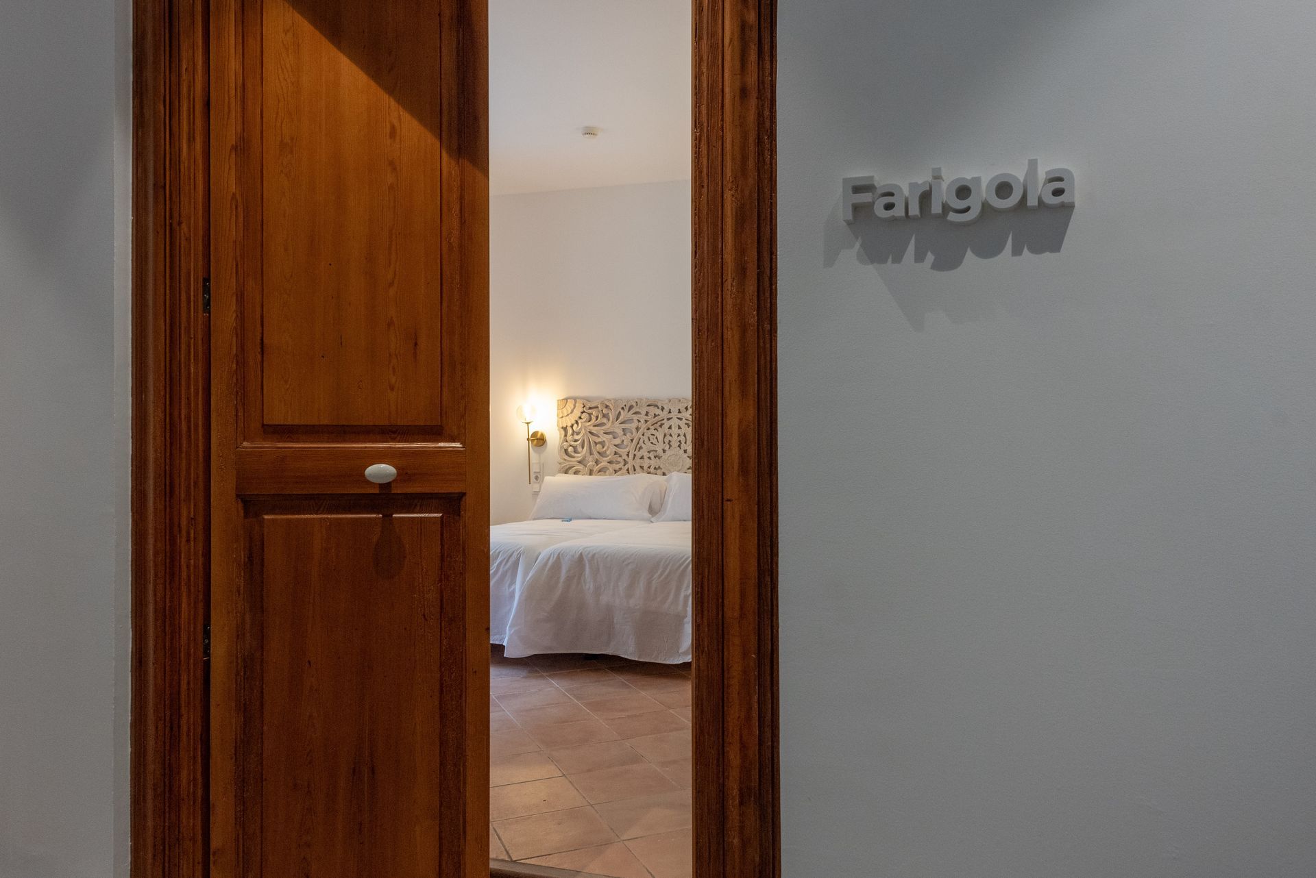 Una puerta de madera se abre a un dormitorio con una cama.
