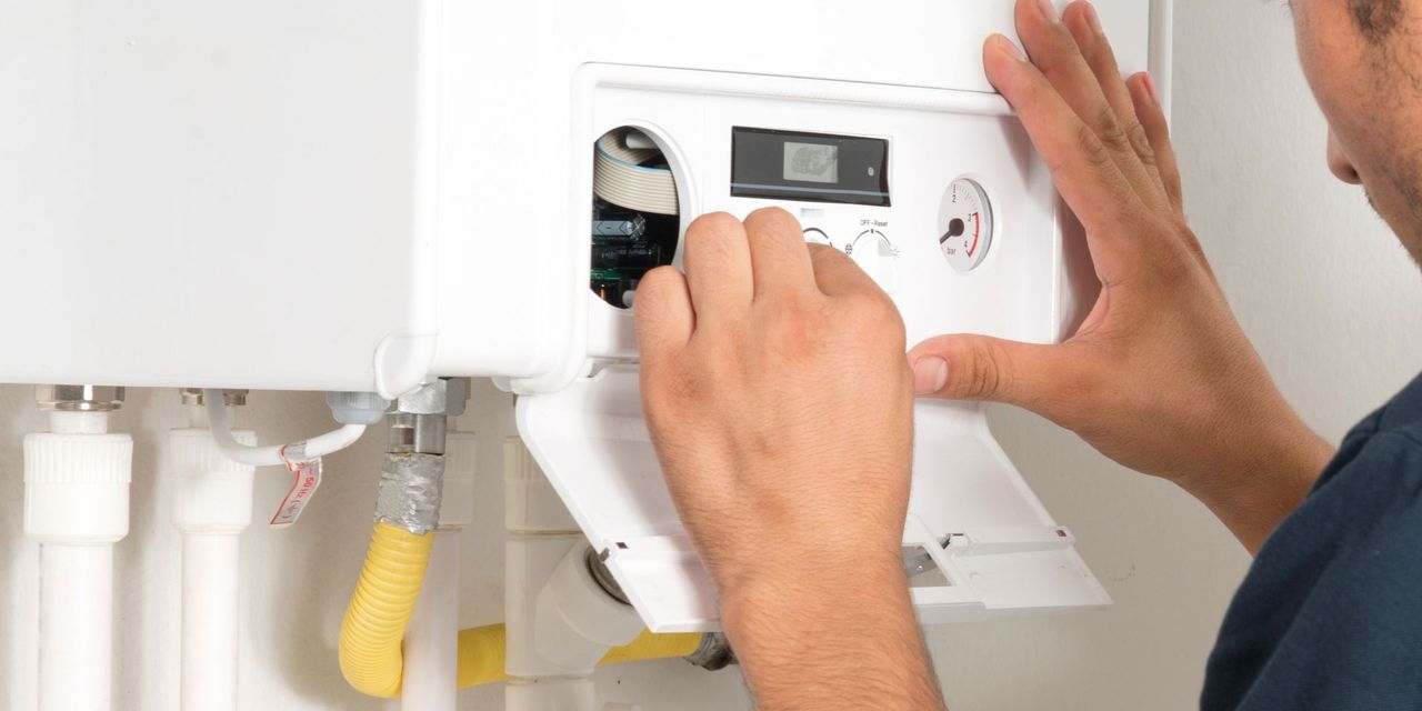A man is fixing a boiler in a bathroom.