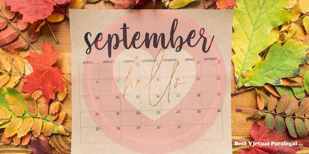 A calendar for september is surrounded by autumn leaves on a wooden table.
