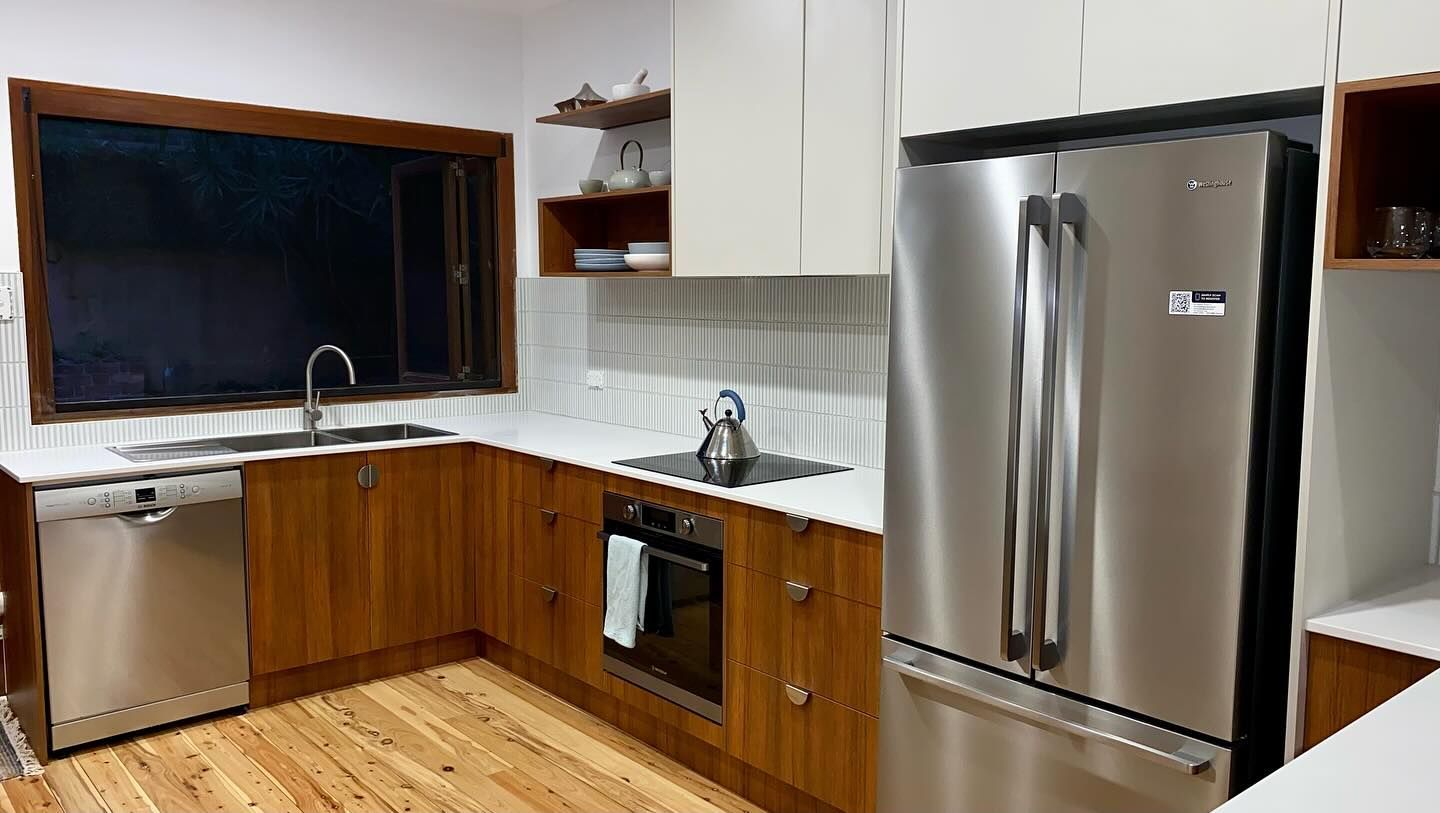 A kitchen with stainless steel appliances and wooden cabinets — Coastal Detail Joinery in Tuncurry, NSW