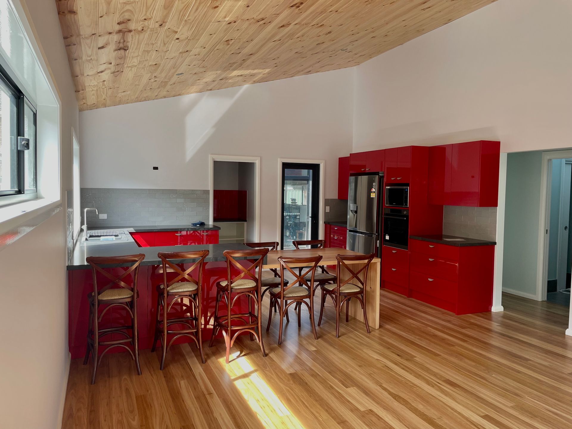 A kitchen with red cabinets , a table and chairs— Coastal Detail Joinery in Tuncurry, NSW
