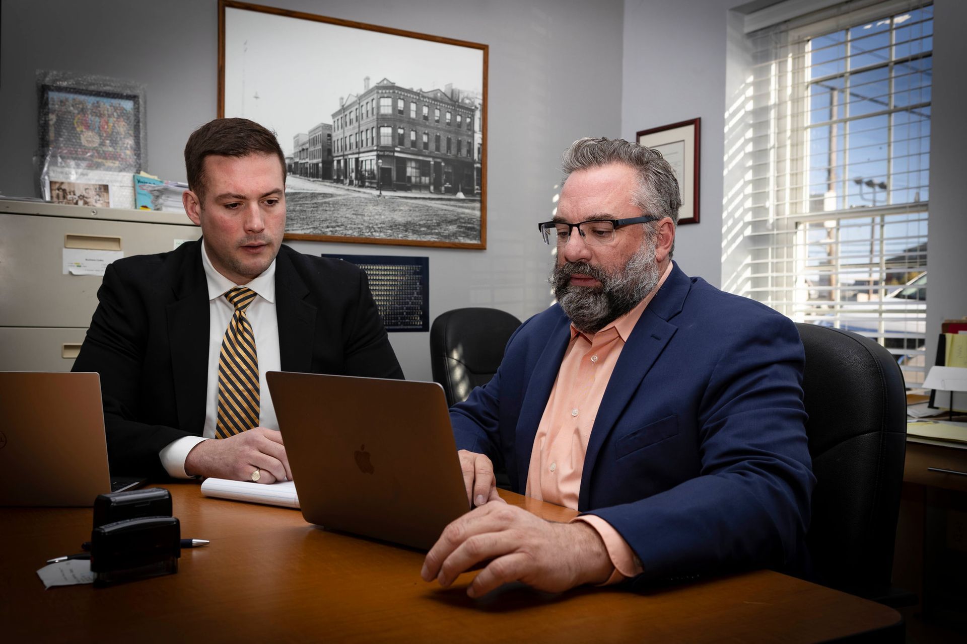 KPP Law Leadership is sitting at a desk looking at a laptop computer.