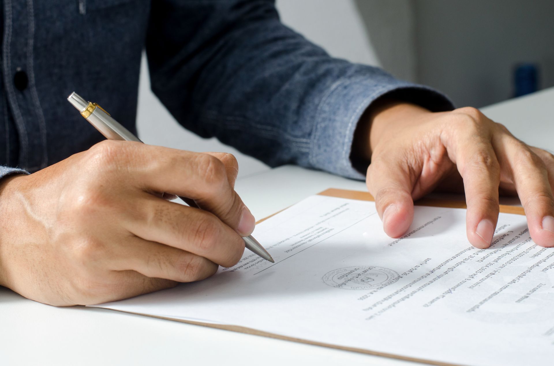 A man is writing on a piece of paper with a pen.