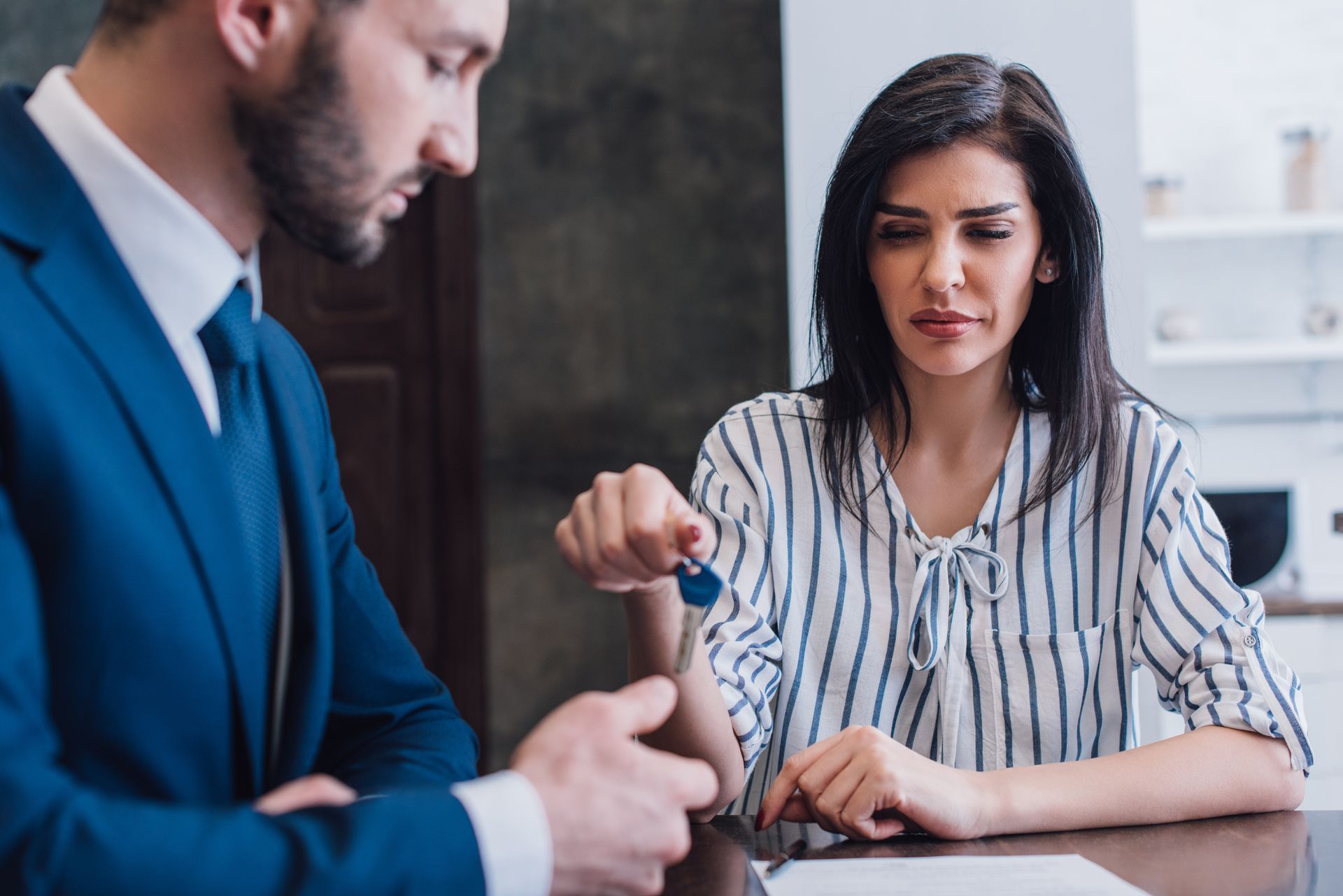 A man in a suit is giving a key to a woman.