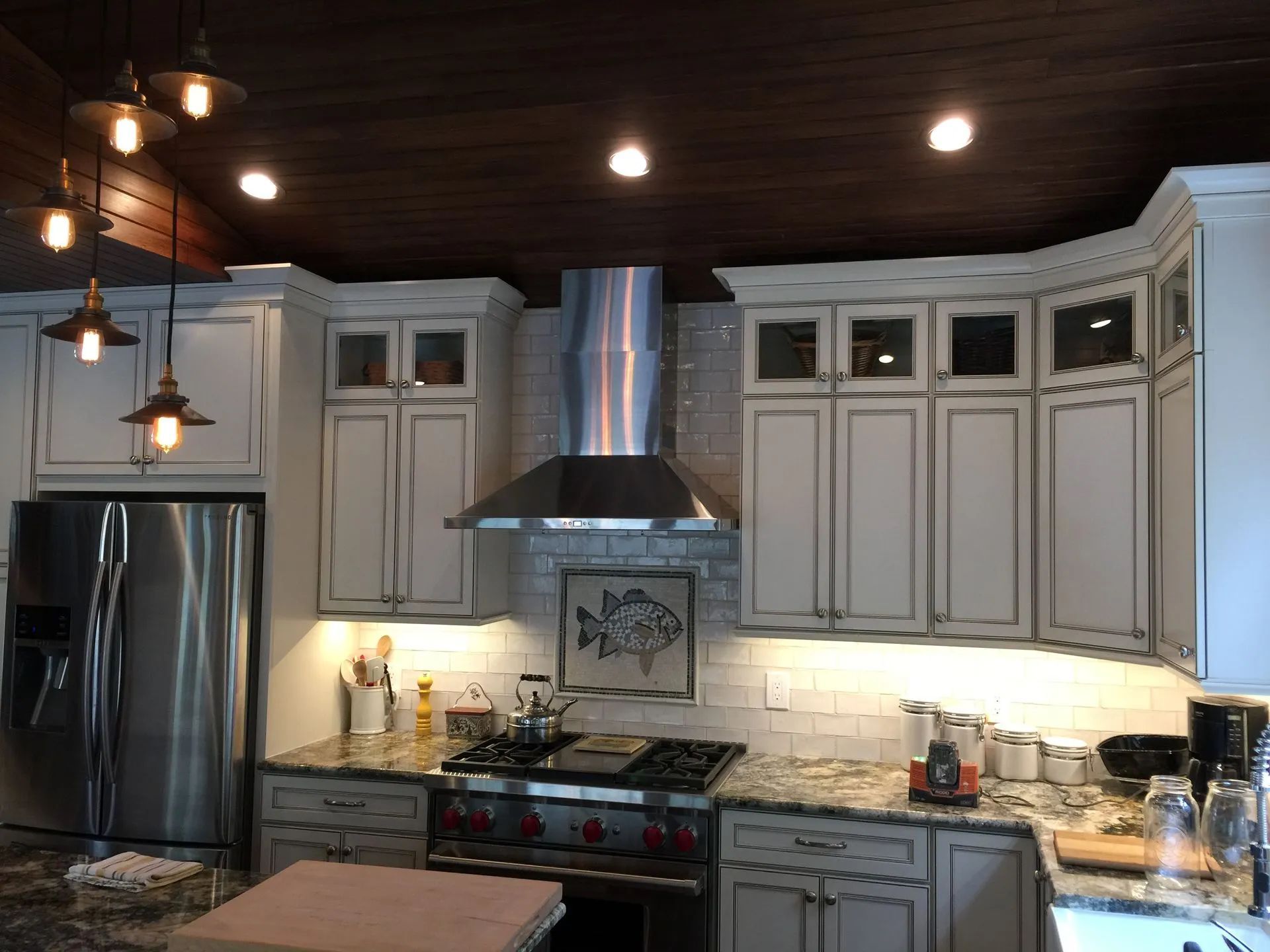 Kitchen with white cabinets, stainless steel appliances, dark wood ceiling, and granite countertops.