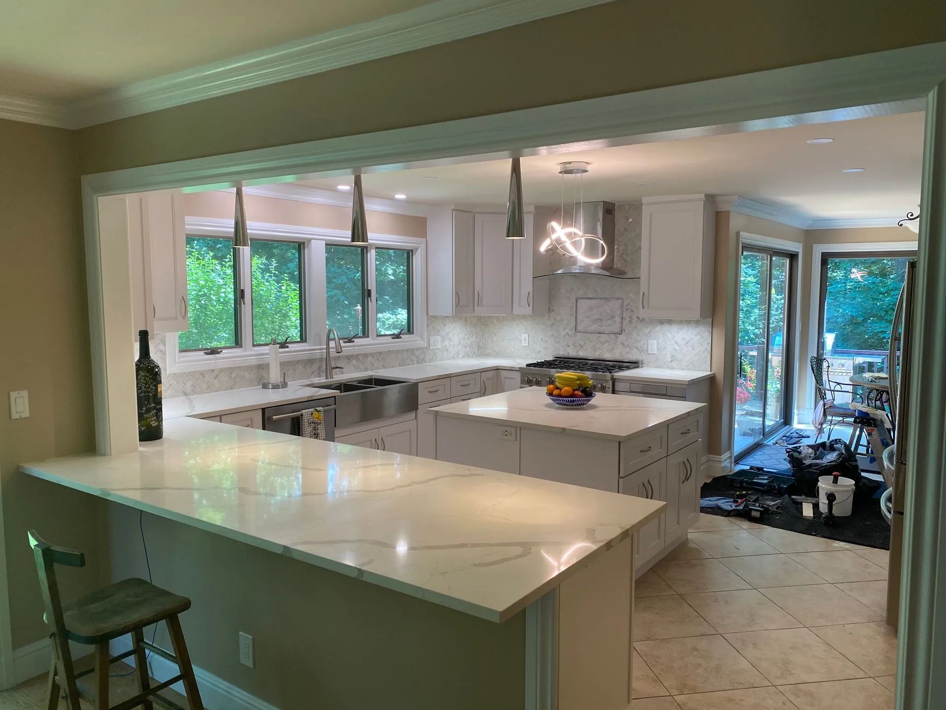 Modern white kitchen with island, quartz countertops, and stainless steel appliances.