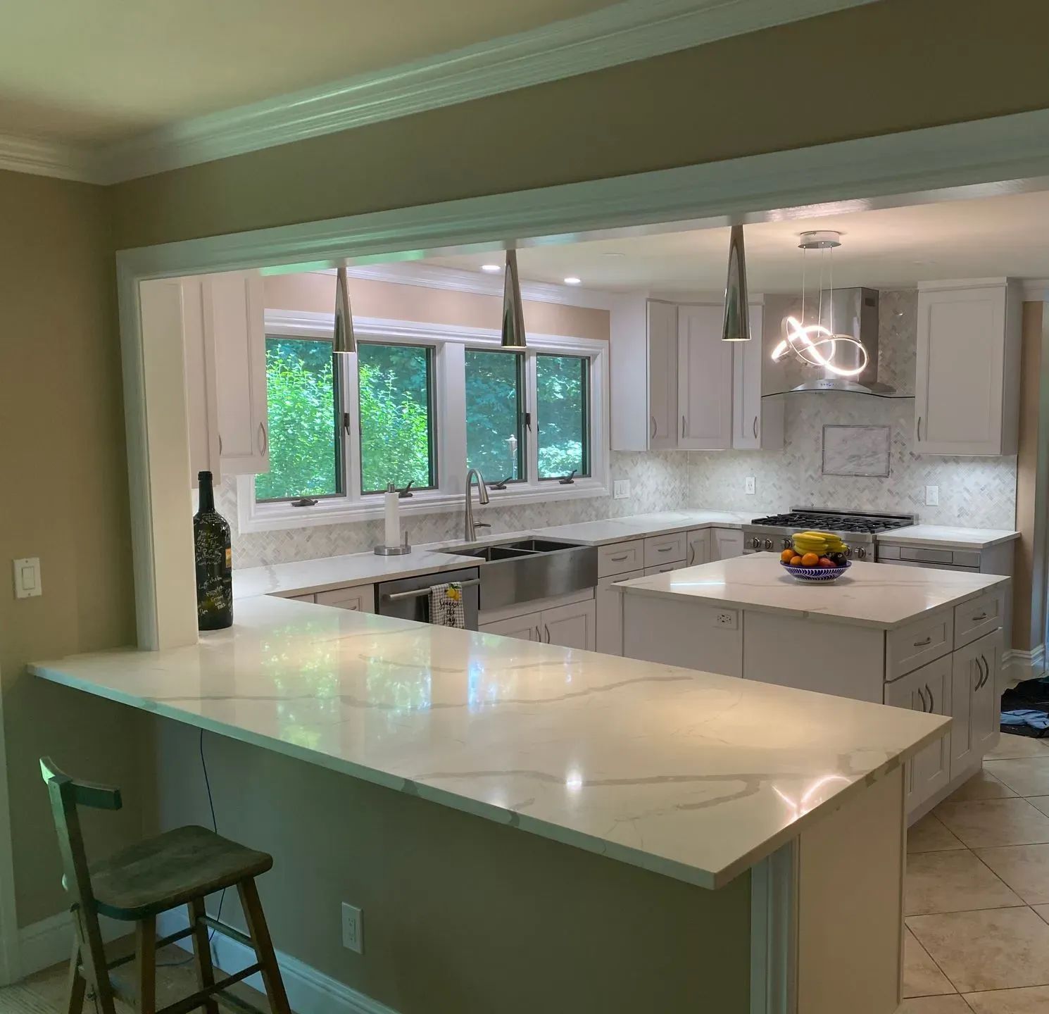Kitchen remodel with white cabinets, island, countertops, and stainless steel appliances.