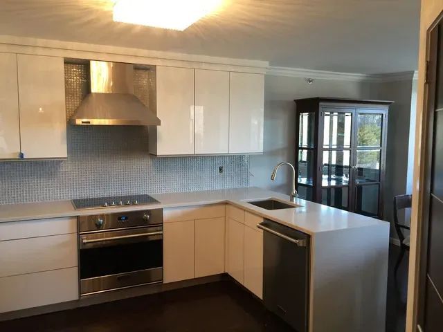 Modern kitchen with white cabinets, stainless steel appliances, and a gray countertop.