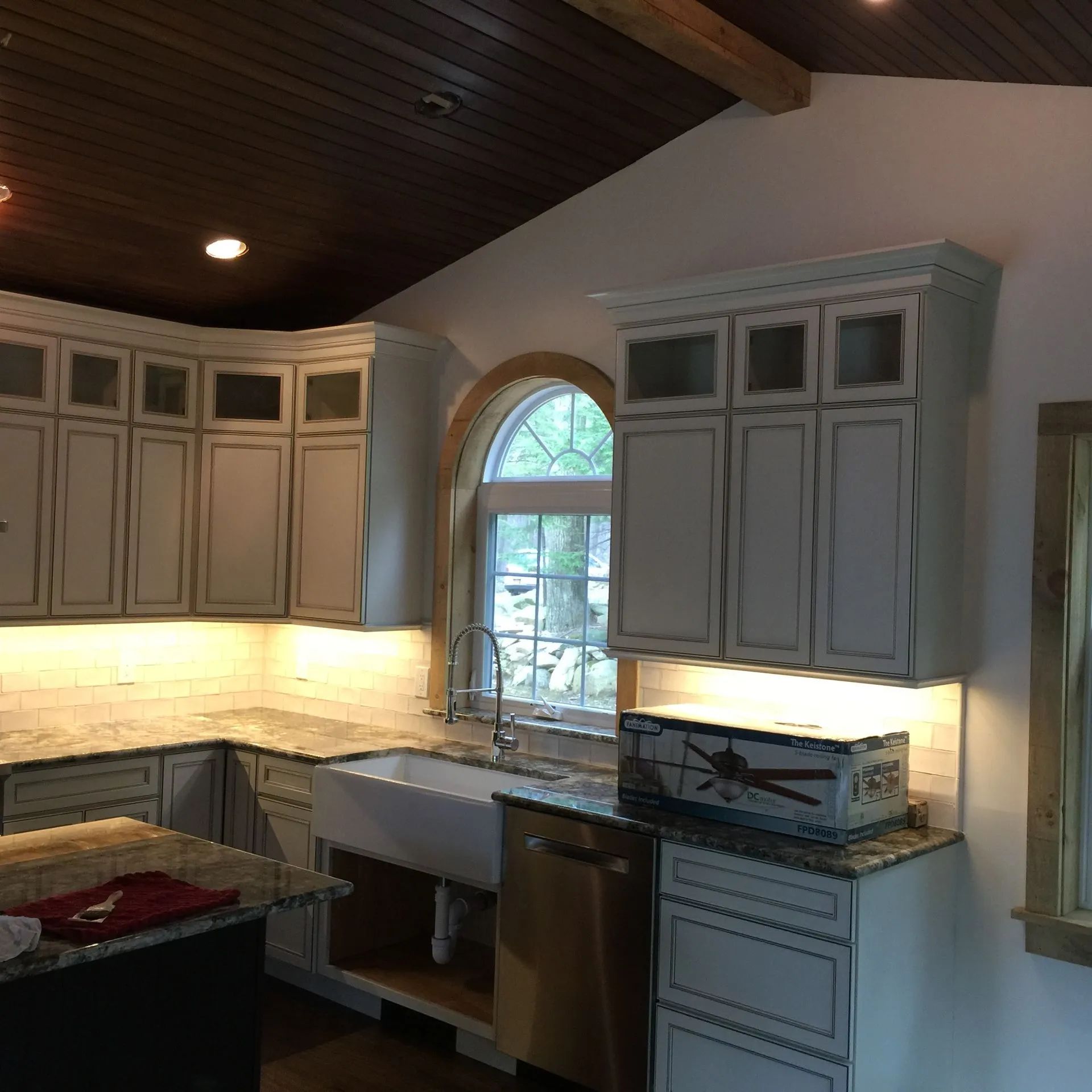 Kitchen with white cabinets, light countertops, and a farmhouse sink. The ceiling is dark wood.