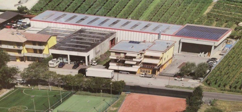 Una vista aerea di un grande edificio con un campo da tennis in primo piano.
