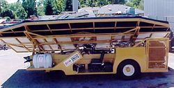 a yellow truck with a large roof is parked in a parking lot .