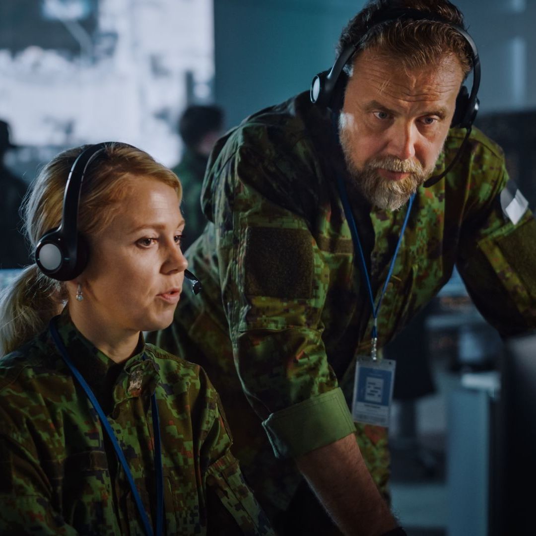 Military personel discuss an issue in a server room, they benefit from Government, Military, & Municipal UPS System Solutions