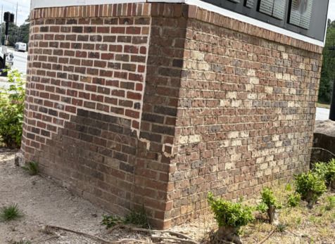 Metro Atlanta brick mason repairs collision-damaged monument base with fresh brick and mortar alongside weathered existing brickwork.