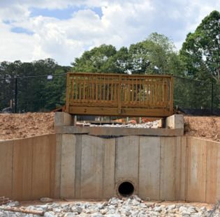 Finished concrete retaining wall installation with drainage pipe by ATL Priority Mason, Metro Atlanta concrete contractor