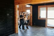 A man and a woman are standing in an empty room in a wooden house.
