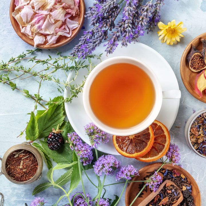 Eine Tasse Tee steht auf einer Untertasse, umgeben von Blumen und Früchten.