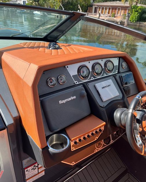 A close up of the dashboard of a boat with a steering wheel.
