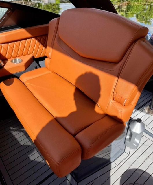 A brown leather seat on a boat with a cup holder
