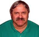 Man with mustache in a green shirt, looking directly at the camera.