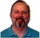 Man with beard and goatee smiling, wearing a blue shirt.