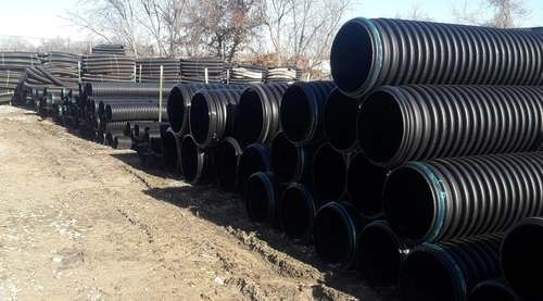 A bunch of black pipes are stacked on top of each other on the ground — Odessa, MO — Continental Pipe Co.