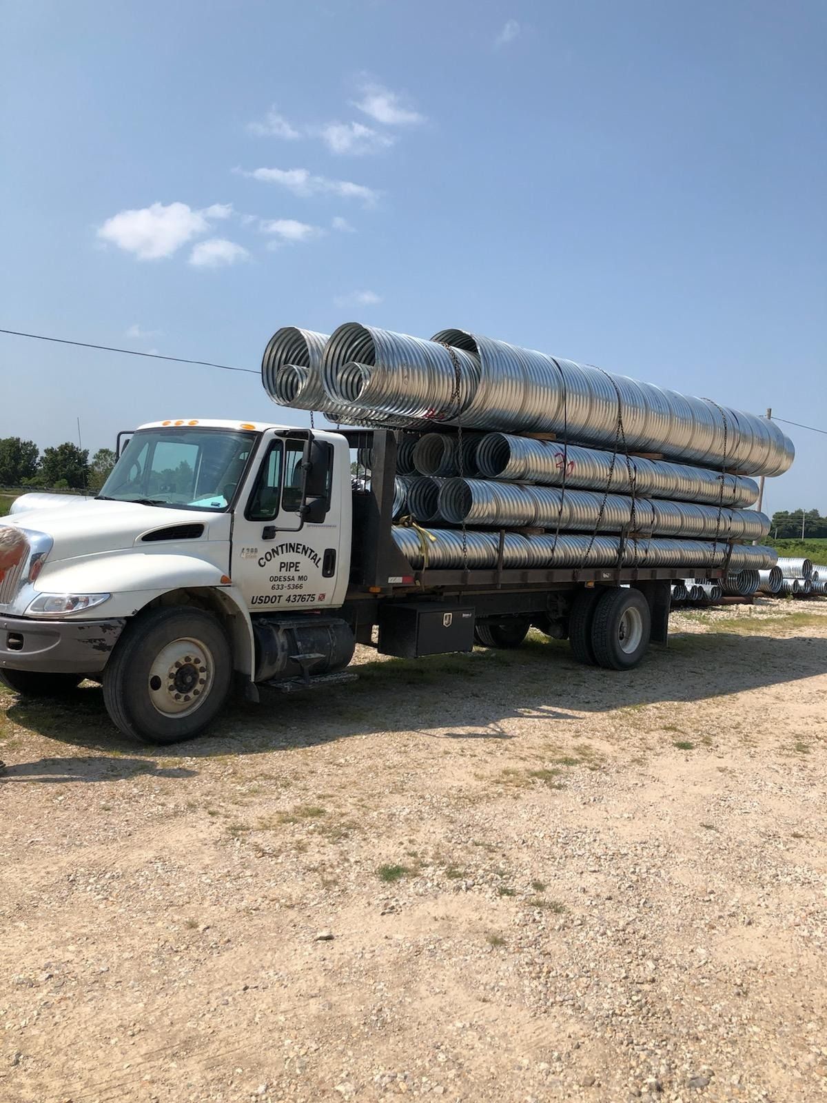 A white truck is carrying a stack of metal pipes — Odessa, MO — Continental Pipe Co.