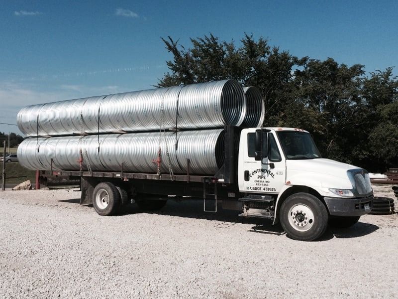 A white truck is carrying a stack of metal pipes — Odessa, MO — Continental Pipe Co.