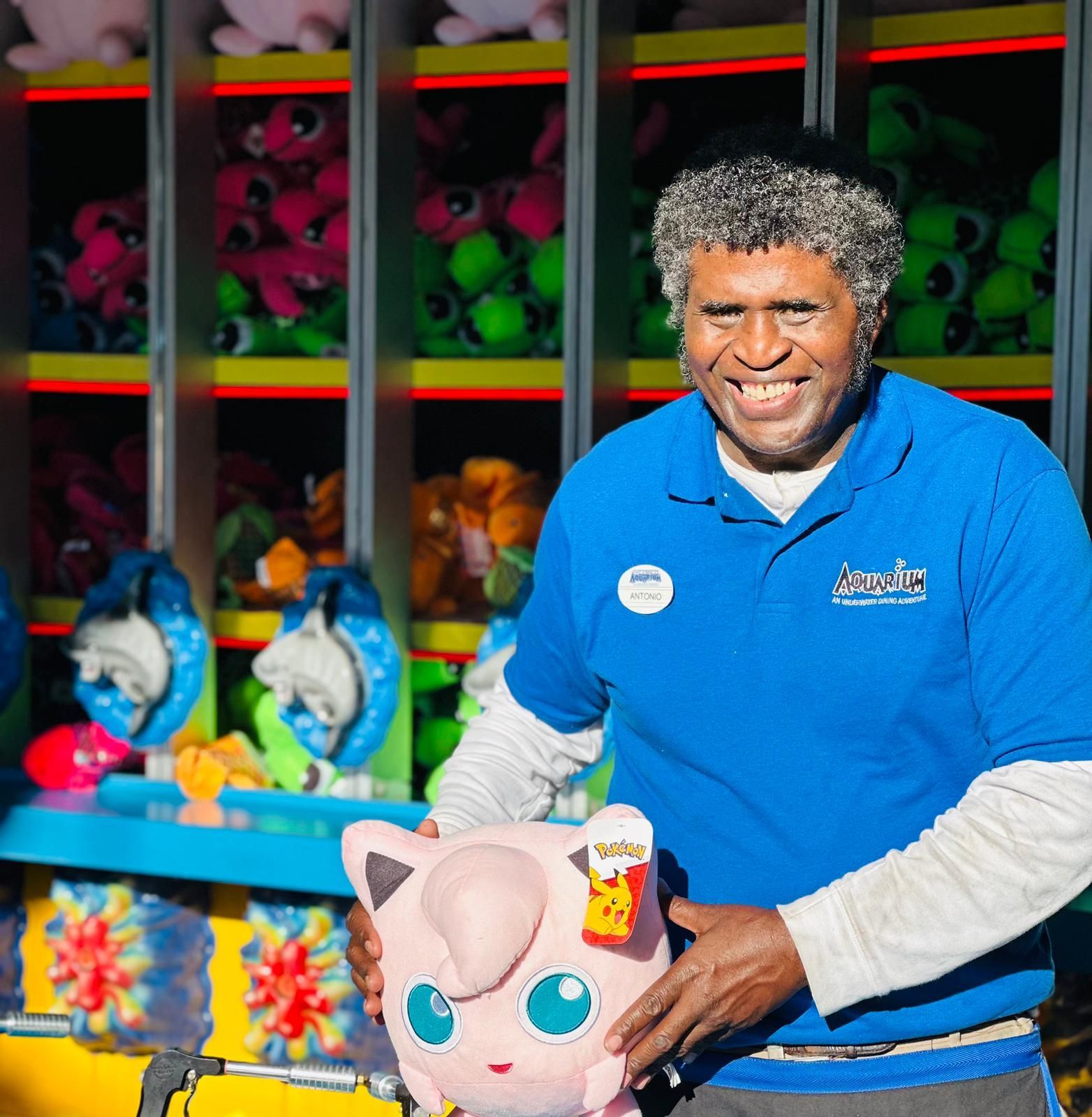 A man wearing a blue shirt holding a stuffed animal