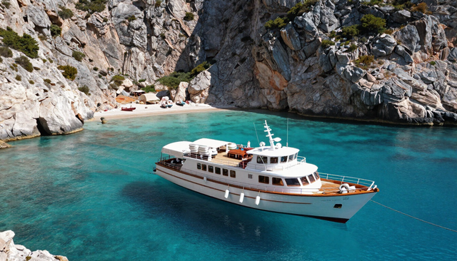 Boutique small ship anchored in a turquoise coastal bay with dramatic cliffs