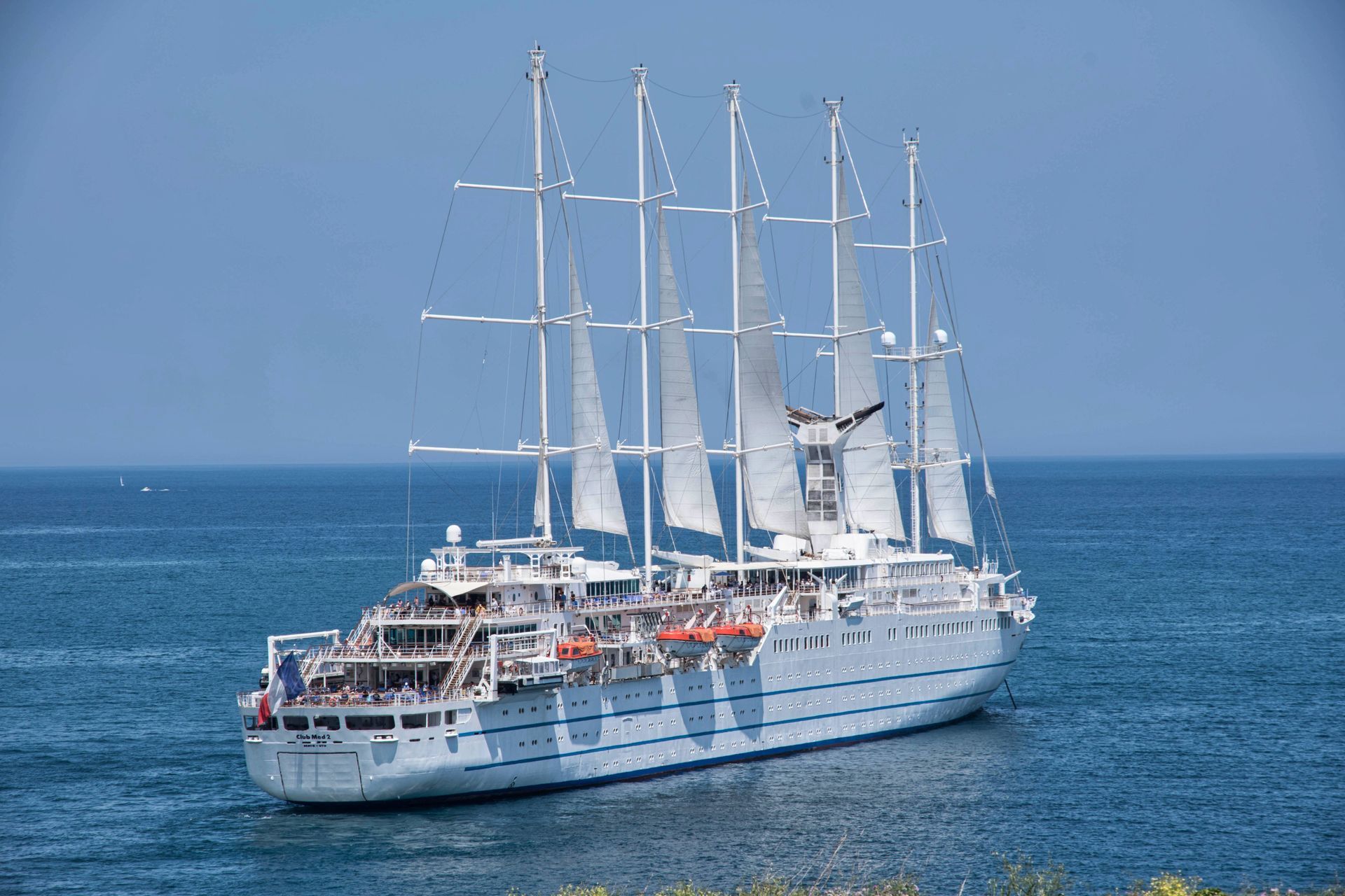 Tall-masted sailing ship under full sail in Mediterranean waters