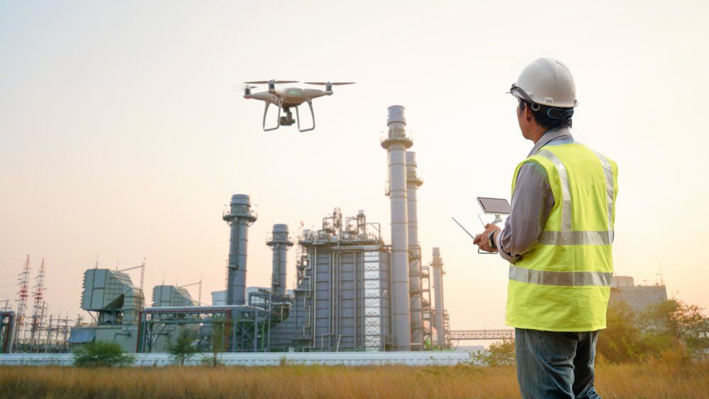 Un homme pilote un drone au-dessus d'une usine.