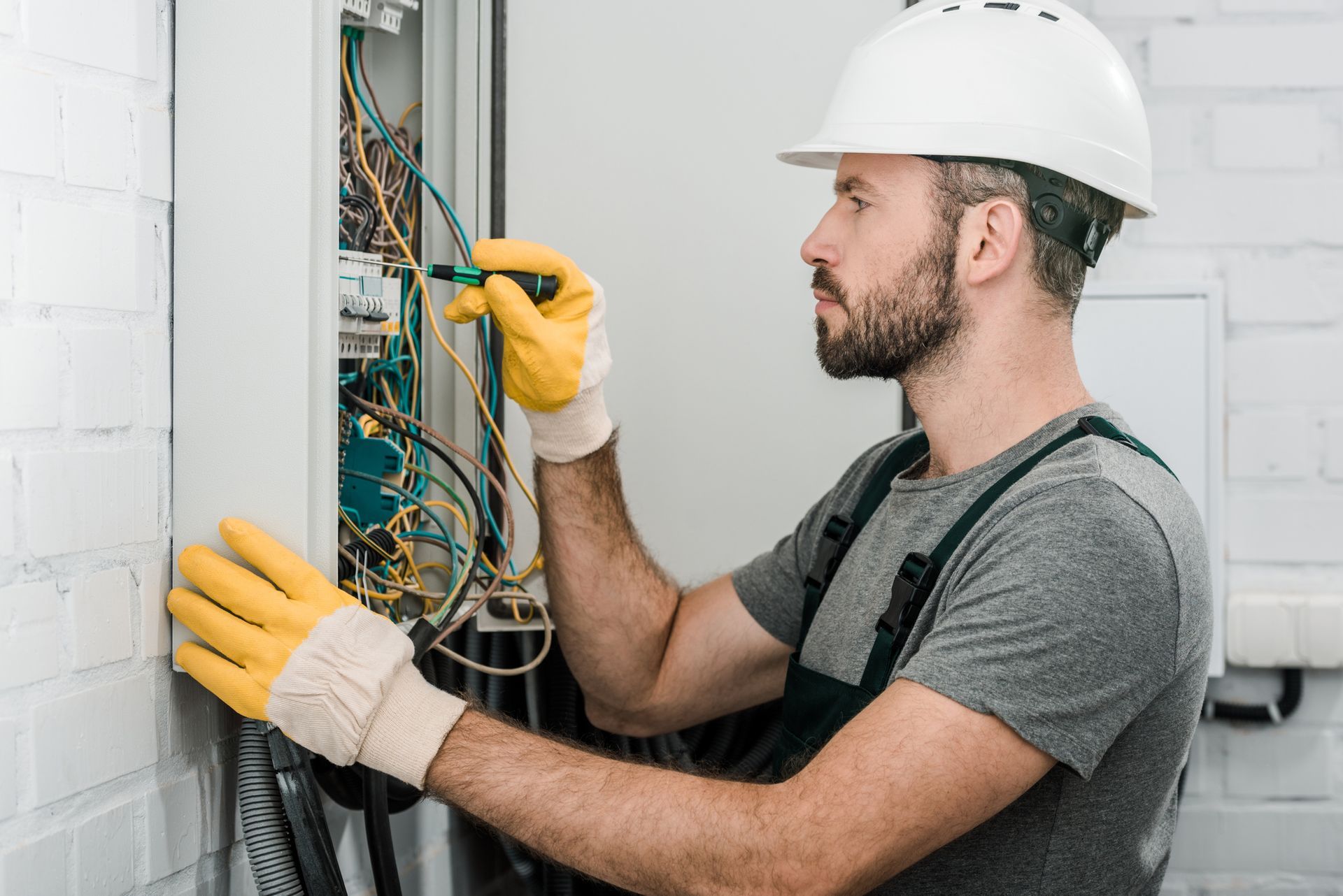 Side view of electrician repairing an electrical box, showcasing commercial electrician services.