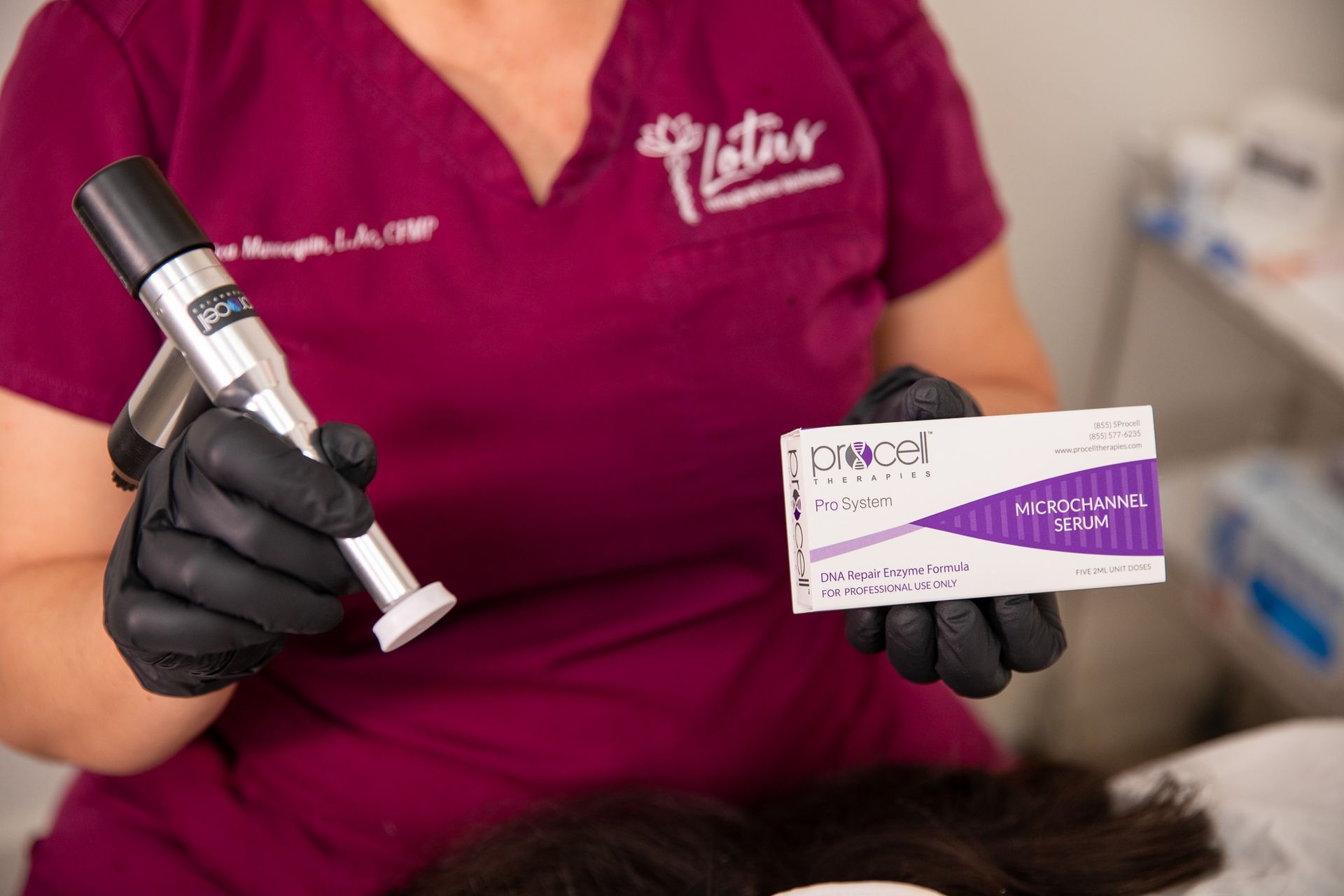 Gloved professional holding a facial tool and a purple-white product card in a clinic setting