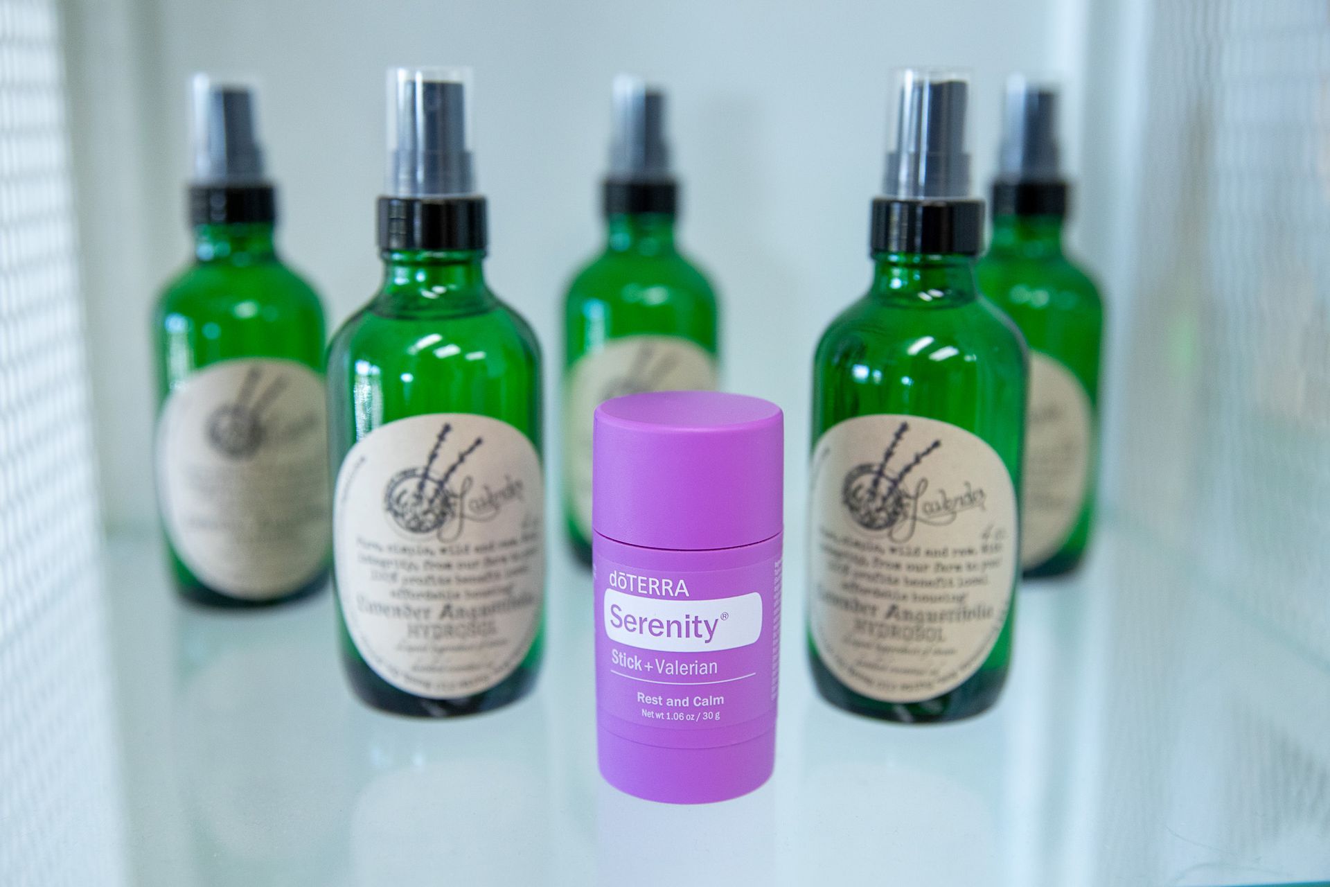Green bottles behind a purple Serenity spray bottle on a light table