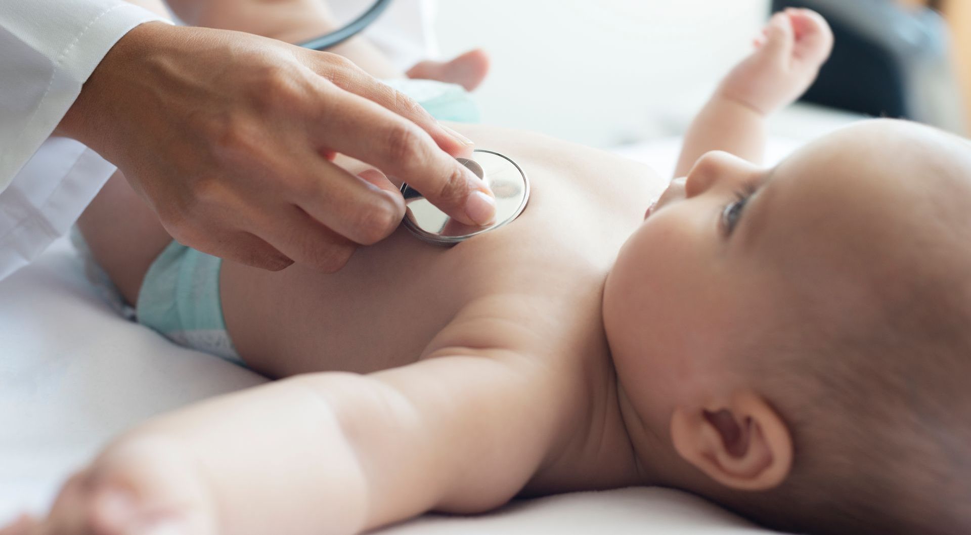 Doctor listening to baby's chest with a stethoscope during a checkup.