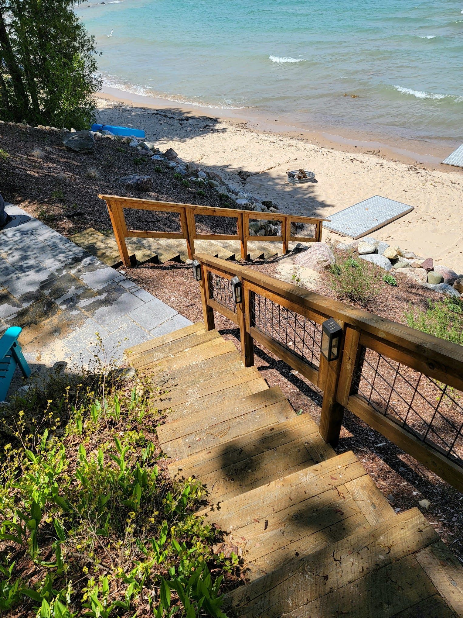 Wooden staircase leading down to a sandy beach with a turquoise sea.
