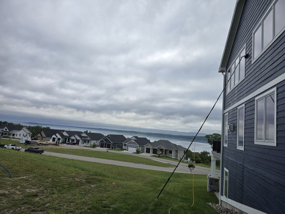 A row of modern houses on a hillside with a cloudy sky. The houses are dark-colored with white trim.