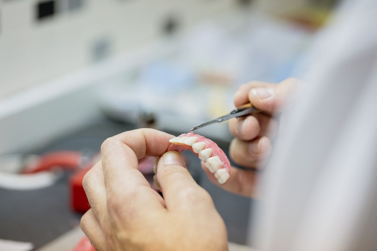Dentist holding dentures, working in a dental lab.
